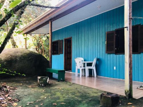 une maison bleue avec une table et une chaise sur une terrasse couverte dans l'établissement Chalé Mar e Montanha, à Trindade