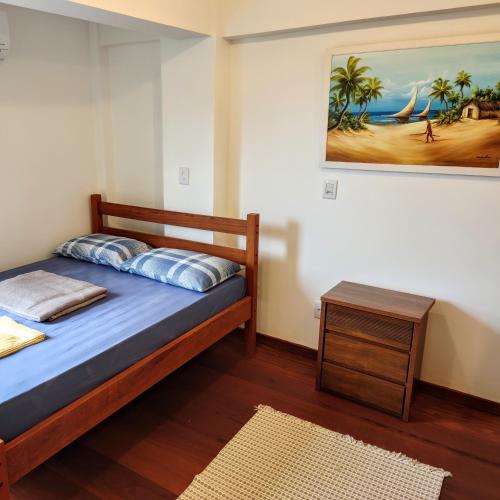 a bedroom with a bed and a table and a painting at The Best View in Angra dos Reis