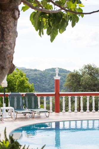 a swimming pool with two lounge chairs next to a fence at Villa PANGALIS Romantica in Kato Pavliana