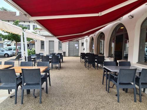 un patio avec des tables et des chaises et un parasol rouge dans l'établissement LE CHAPON BRESSAN, à Branges