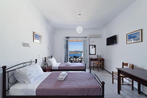 a bedroom with two beds and a table and a desk at Villa Aegeo Studios in Batsi