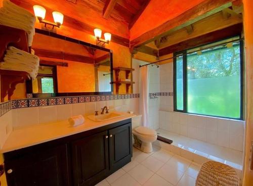 a bathroom with a sink and a toilet and a window at Hacienda San Juan de La Vega in Otavalo