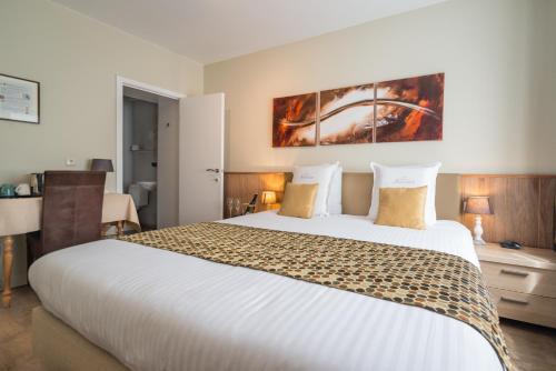 a hotel room with a large white bed and a desk at Hotel Maraboe in Bruges