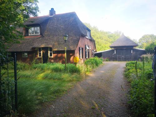 uma casa antiga com um telhado de palha ao lado de uma estrada em Het Nijhuisje em Markelo