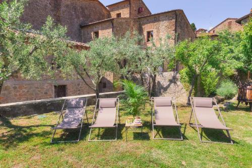 a group of chairs in the yard of an old building at Il Giardino del Cardinale - Deb'S Monticchiello in Monticchiello