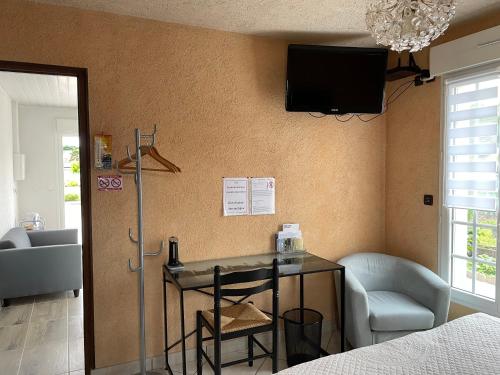a room with a table and a tv on the wall at Studio indépendant chez l'habitant in Olivet