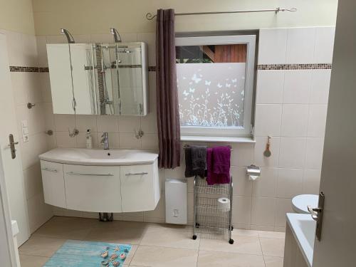 La salle de bains est pourvue d'un lavabo, d'un miroir et d'une fenêtre. dans l'établissement Ruhiges Ferienhaus Wandlitz, à Wandlitz