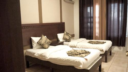una habitación de hotel con 3 camas en una habitación en Al Fawanes Hotel Apartments, en Amán