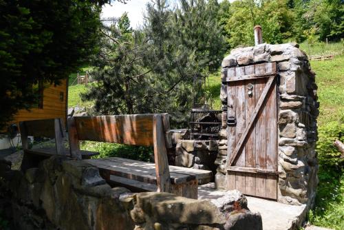 a wooden bench and a wooden door in a stone wall at Cisówka Pokoje Gościnne in Piwniczna
