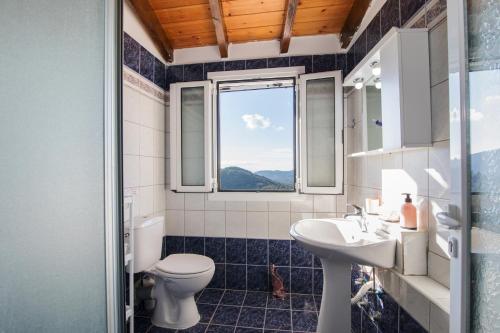 a bathroom with a toilet and a sink and a window at Villa PANGALIS Romantica in Kato Pavliana