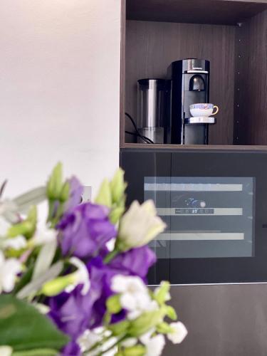 un vase de fleurs assis à côté d'une machine à café dans l'établissement Grand 2 pieces Gray d'Albion, à Cannes