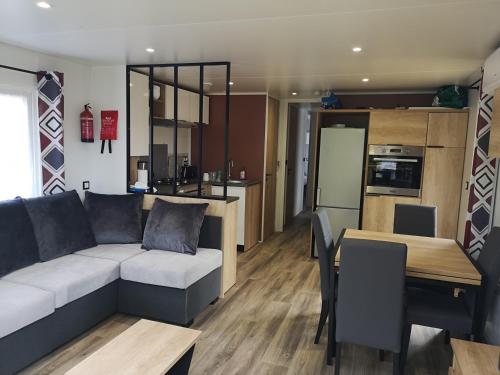 a living room and kitchen with a couch and a table at Mobilhome Les Viviers - Cap Ferret in Lège-Cap-Ferret