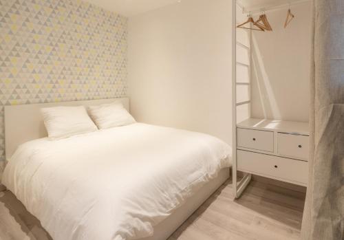 Cette petite chambre comprend un lit blanc et une commode. dans l'établissement Le cocon du Vieux-Port, à Marseille