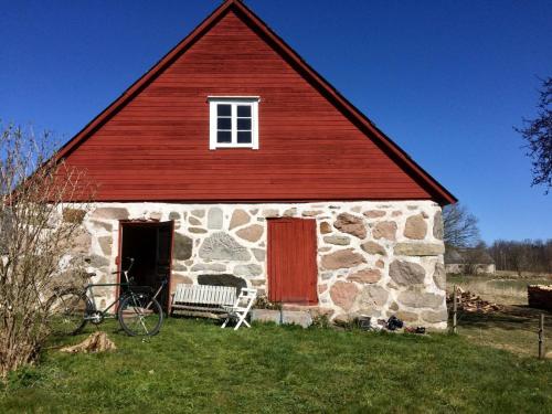 ein altes Steingebäude mit einer roten Tür und einer Bank in der Unterkunft Yxnaholma Rum in Höör