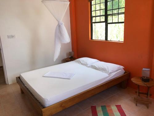 a bed in a room with an orange wall at Joy's Apartment in Roseau