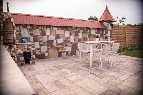 a patio with a table and chairs and a stone wall at Przystanek Czasu - domek kopułowy in Sułów