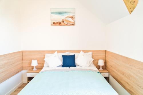 a bedroom with a bed with blue and white pillows at Promyki - Domki Apartamentowe in Chłopy