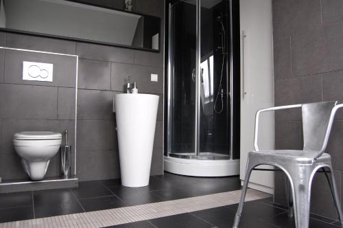 a bathroom with a toilet and a chair in it at Kunsthaus Apartments in Vienna