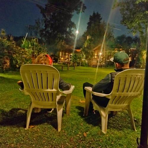 a man and a woman sitting in chairs in the grass at Cabañas Burdeos in Tigre