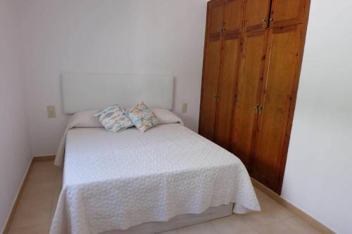 1 dormitorio con cama blanca y armario de madera en Casa Pelícano en Son Parc
