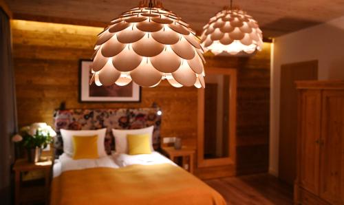 a bedroom with a bed and two chandeliers at Apartamenty u Harrego BOUTIQUE SPA z klimatyzacja, balkon, sauna, tężnia parking in Kudowa-Zdrój