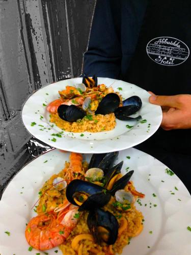 a person holding two plates of food with seafood at Abbaidda Hotel in Valledoria