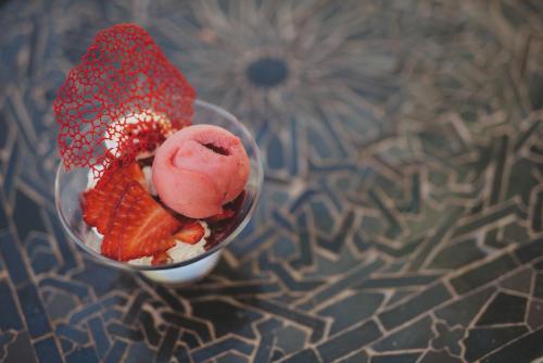 a bowl of ice cream and strawberries on a table at Les Deux Tours in Marrakech