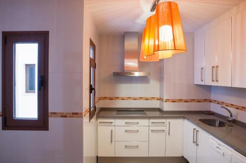 a kitchen with white cabinets and an orange light at Real de Cartuja Apartments & Suites in Granada