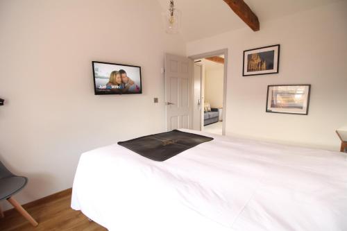 a white bed in a room with a tv on the wall at Number 8 in Canterbury