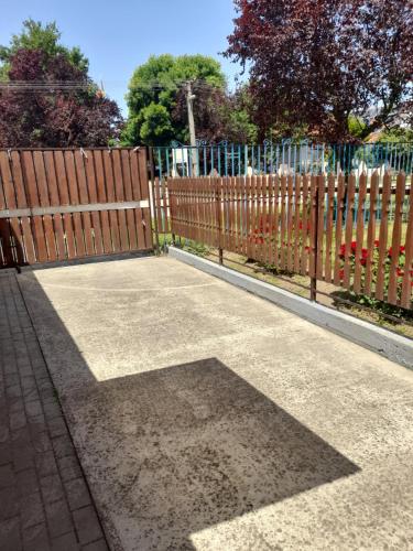 a wooden fence and a sidewalk with a gate at Thermál Apartman Tiszafüred in Tiszafüred