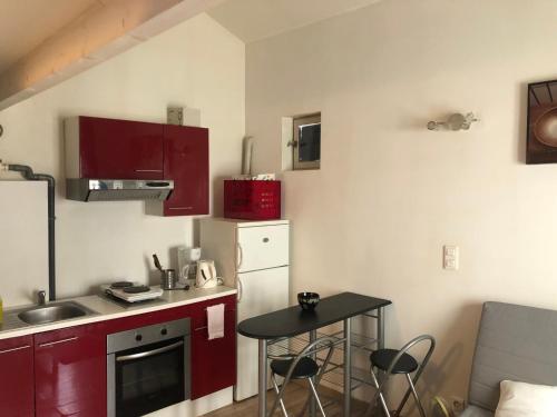 eine kleine Küche mit roten Schränken und einem kleinen Tisch in der Unterkunft Studio de la Croix avignon centre in Avignon