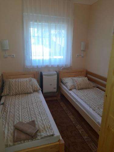 two beds in a small room with a window at Thermál Apartman Tiszafüred in Tiszafüred