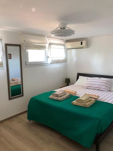 1 dormitorio con 1 cama con sábanas verdes y espejo en Sole e Luna, en Marina di Modica