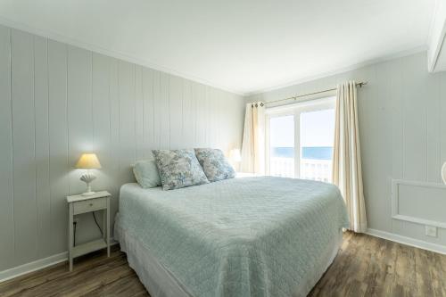 a white bedroom with a bed and a window at Charming Ocean-view Condo at Ocean Pier 3 in Myrtle Beach