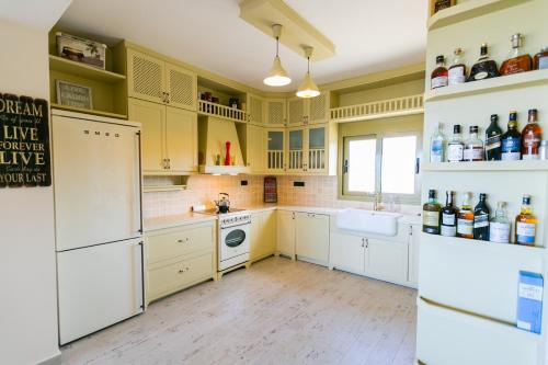 a kitchen with yellow cabinets and a white refrigerator at Aphrodite Villa in Loutraki