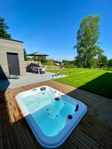 a hot tub on a deck with a yard at La Grange du Logis in Waimes