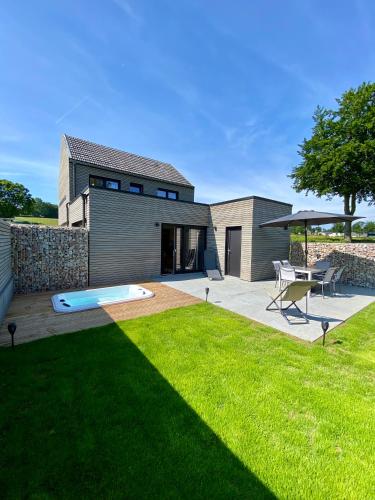 a backyard with a house with a pool and a lawn at La Grange du Logis in Waimes