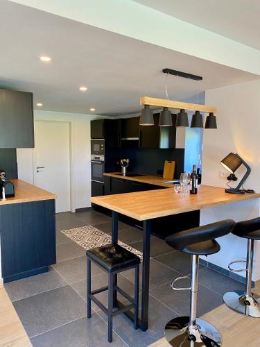a kitchen with a wooden table and some bar stools at La Grange du Logis in Waimes