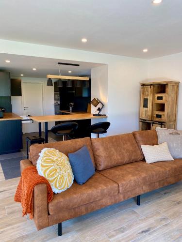 a living room with a brown couch and a kitchen at La Grange du Logis in Waimes