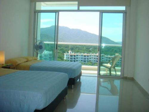 a bedroom with two beds and a chair and a window at Costazul Suites 705 in Santa Marta
