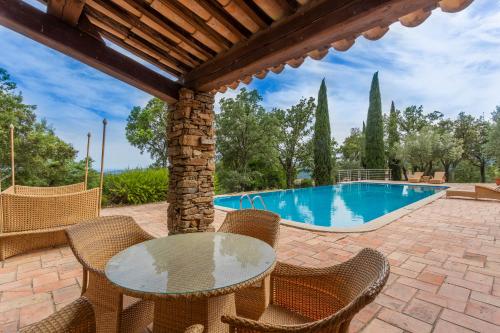 un patio avec une table et des chaises et une piscine dans l'établissement Domaine des Chênes de la Galline, à La Garde-Freinet