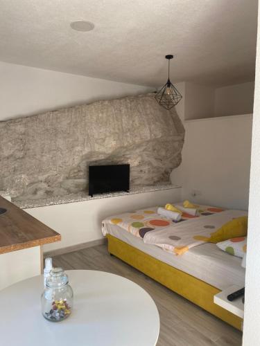 Casa Calda Apartments في ستنيي: غرفة نوم بسرير وتلفزيون على جدار