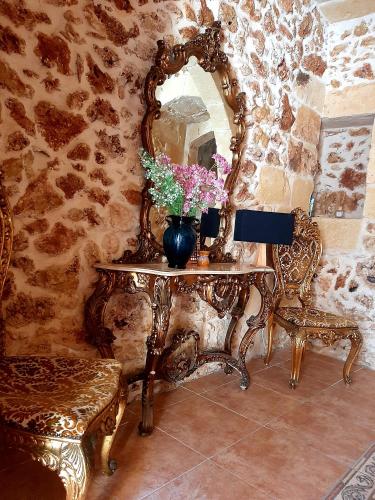 a table with a mirror and a vase with flowers on it at The LYNDEE HOUSE in Nadur