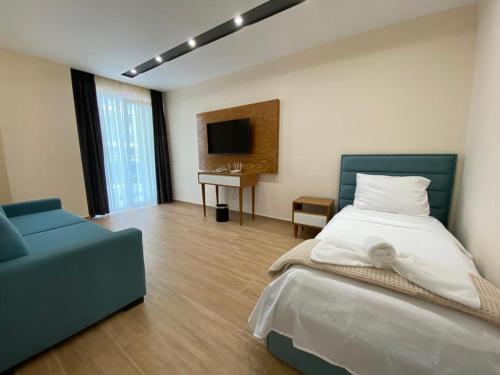 ein Schlafzimmer mit einem Bett, einem Sofa und einem TV in der Unterkunft Milenium Hotel in Shëngjin