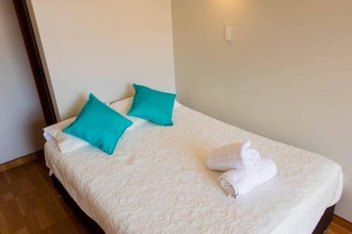 a white bed with blue pillows and towels on it at Casa Fideranda Apartments in Cusco