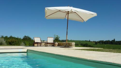 una sombrilla y 2 sillas junto a una piscina en Chambres d'Hôtes La Treille, en Ligardes