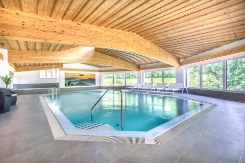 a swimming pool in a house with a wooden ceiling at Hotel Forellenhof in Flachau