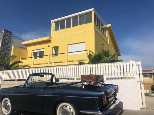 a blue truck parked in front of a yellow house at Casa Margarida in Apúlia