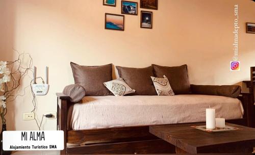 un sofá en una sala de estar con fotos en la pared en M I A L M A Departamento Turistico en San Martín de los Andes