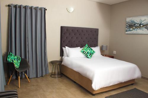 a hotel room with a bed and a chair at Ndalo Lodge Oshoek in Oshoek